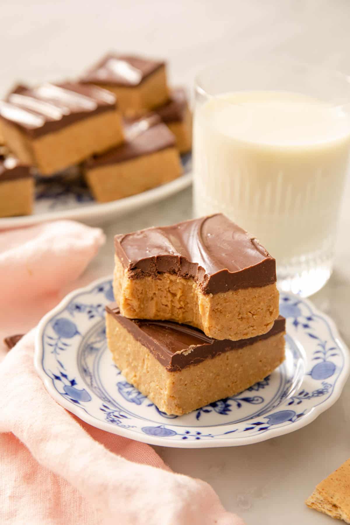 A close up of two peanut butter bars on top of each other, one with a bite out