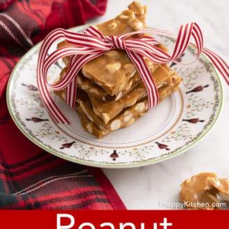 pieces of peanut brittle stacked on a christmas plate with a bow