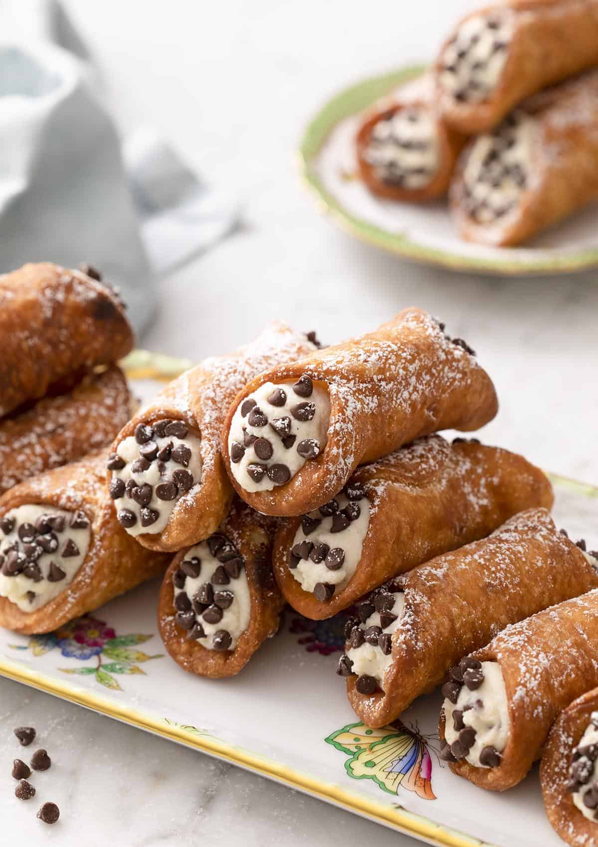 A pile of cannoli on a porcelain tray.