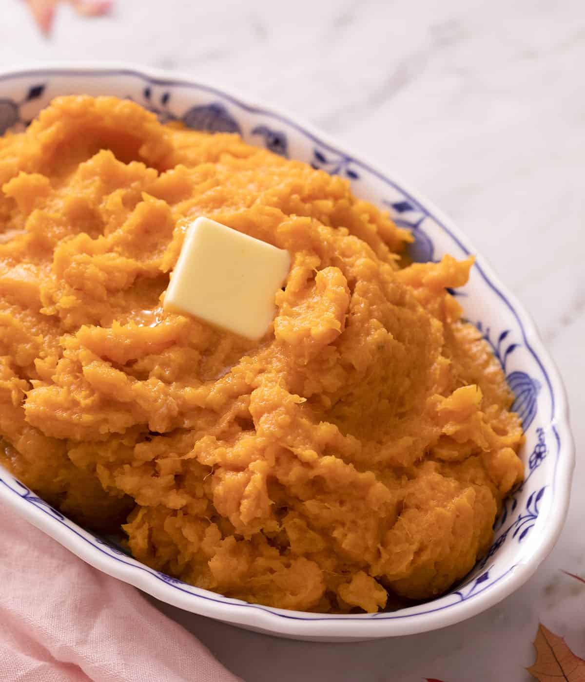 An oval blue and white bowl with mashed sweet potatoes.