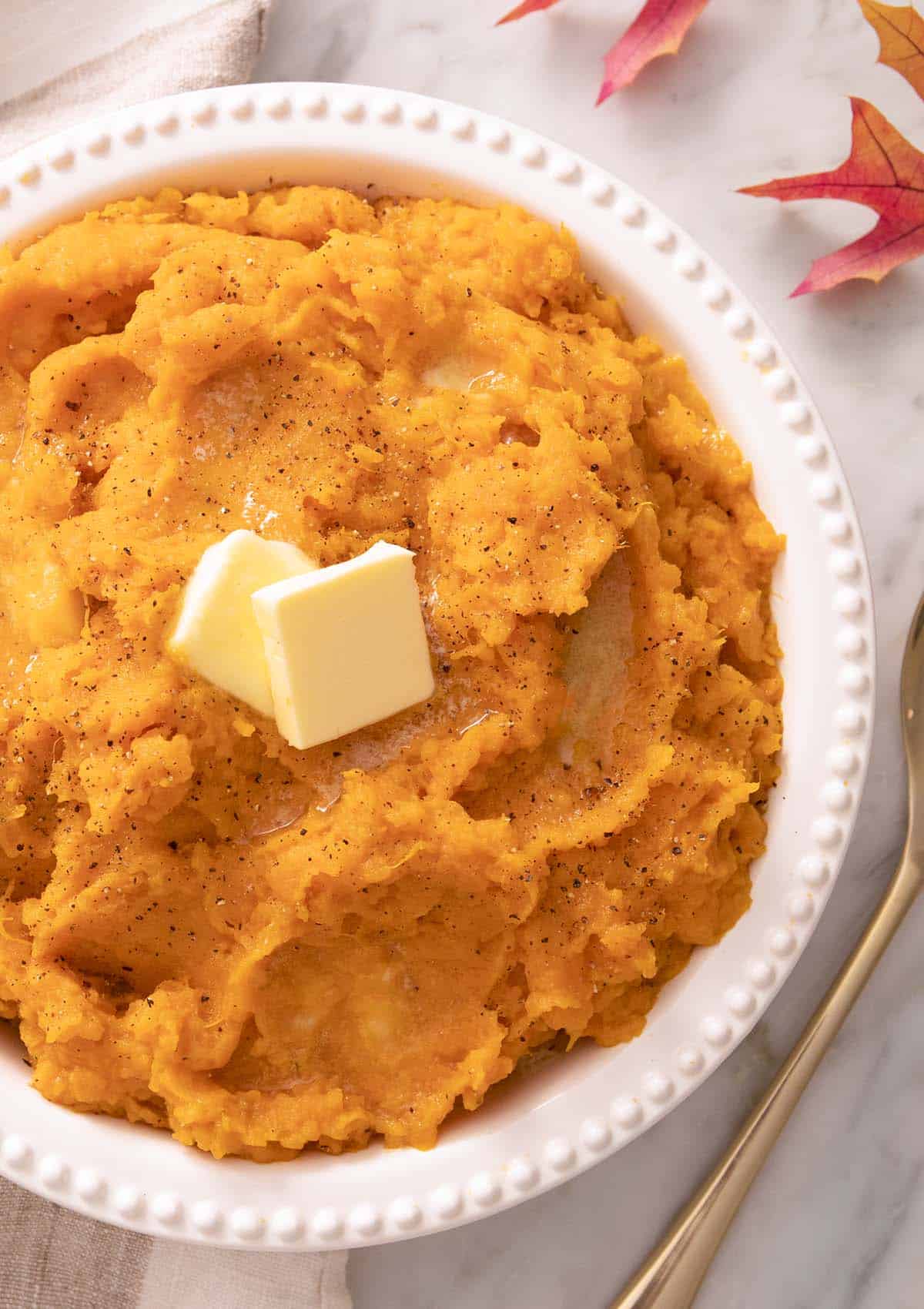 A bowl of mashed sweet potatoes on a marble counter.