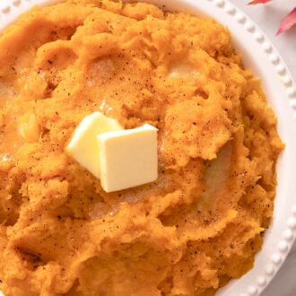 Mashed sweet potatoes topped with pats of butter and black pepper.