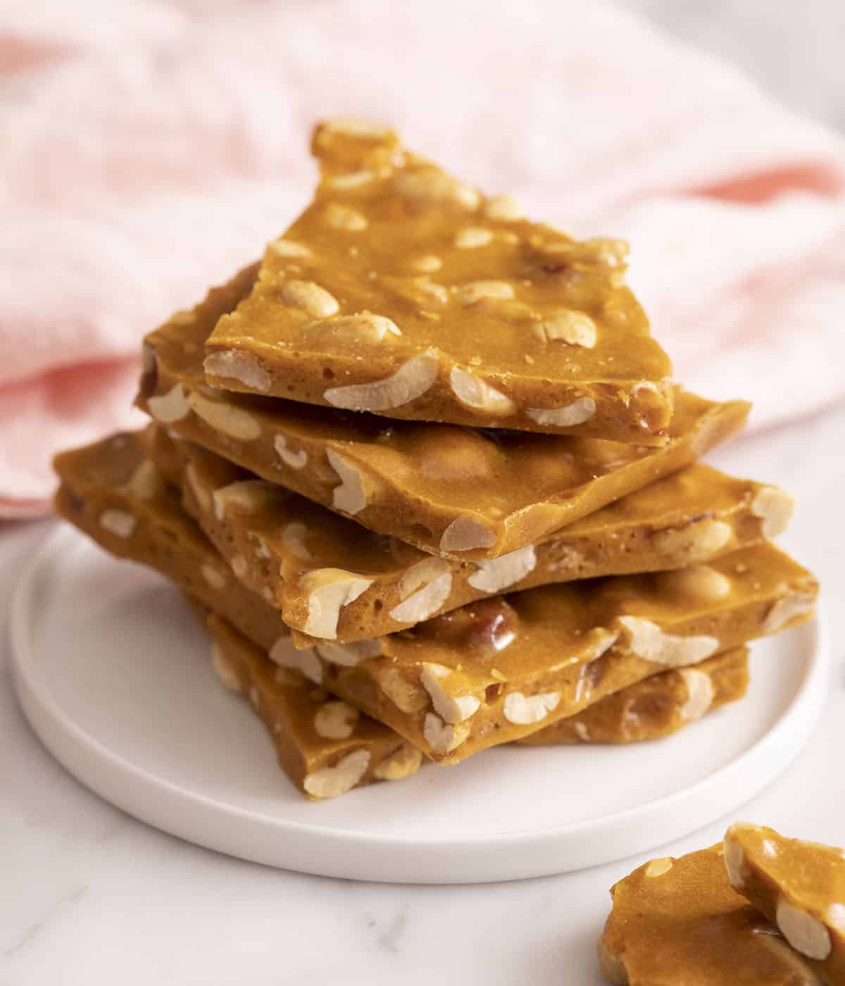 A stack of peanut brittle on a small white plate.