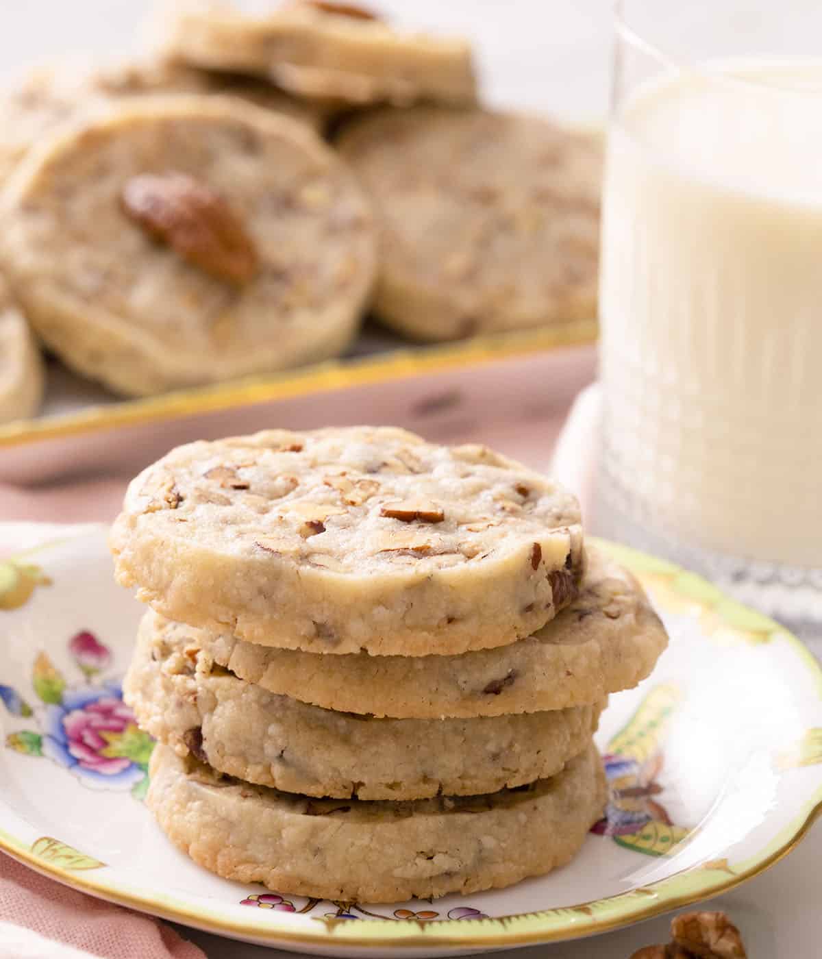 Four pecan sandies next to a glass of milk.