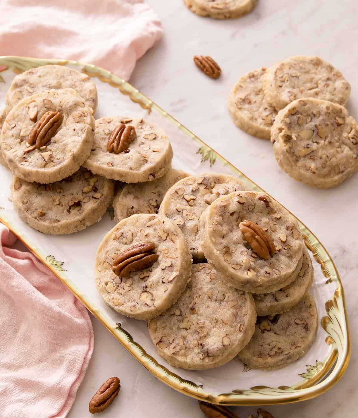 A porcelain serving dish with pecan sandies on top.