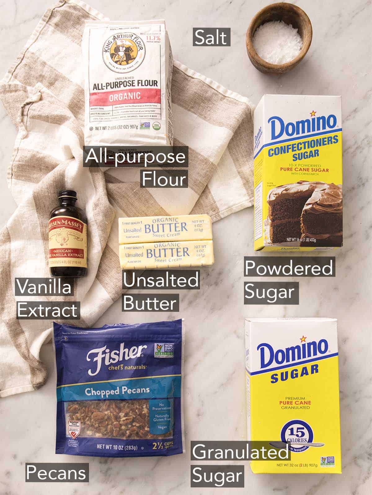 Ingredients to make pecan sandies on a marble counter.