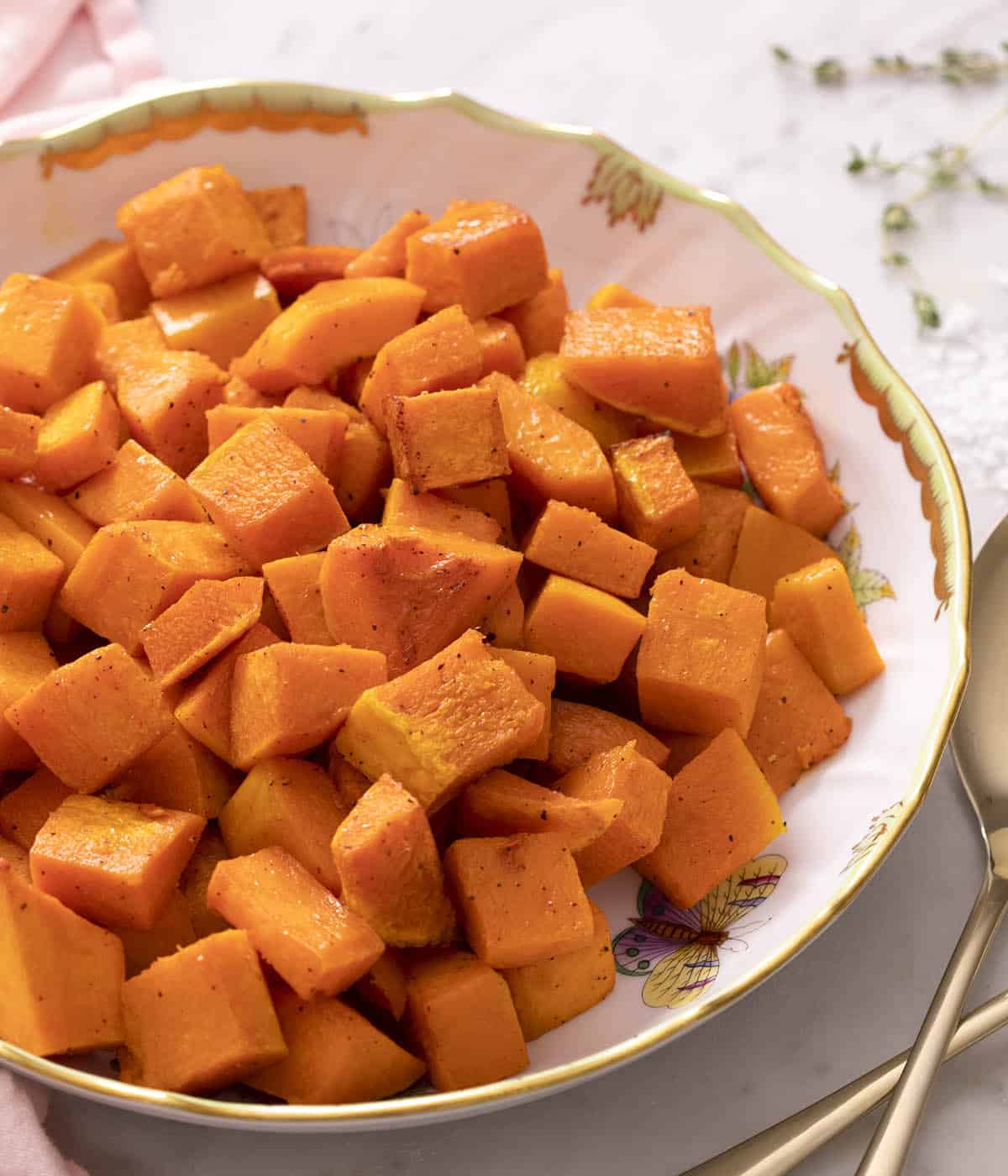 A round porcelain serving bowl filled with roasted butternut squash.