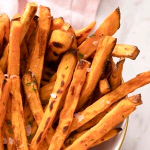 Sweet potatoe fries with sea salt in a white bowl.