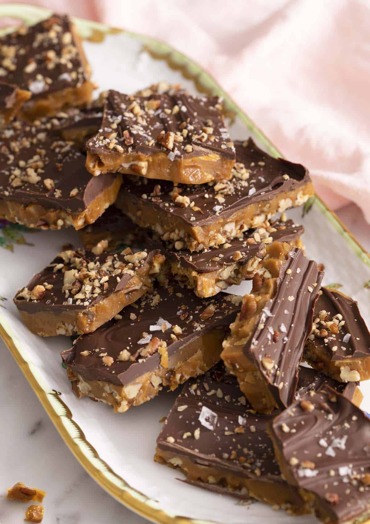 Toffee pieces topped with chocolate on a tray.