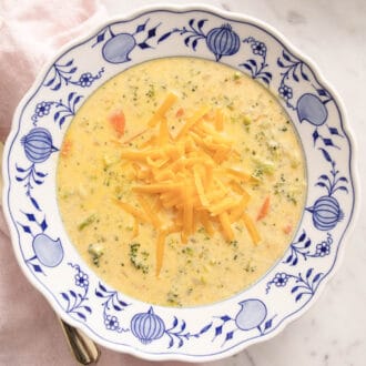 A blue and white bowl with homemade broccoli cheese soup inside.