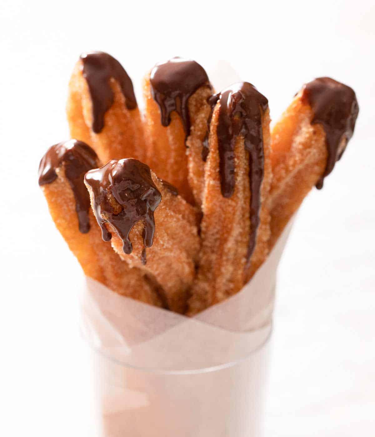 A stack of chocolate dipped churros wrapped in parchment paper
