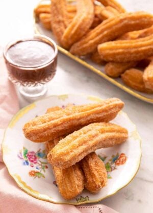 Churros on a plate with chocolate sauce in the background