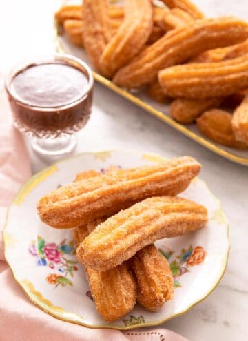 Churros on a plate with chocolate sauce in the background