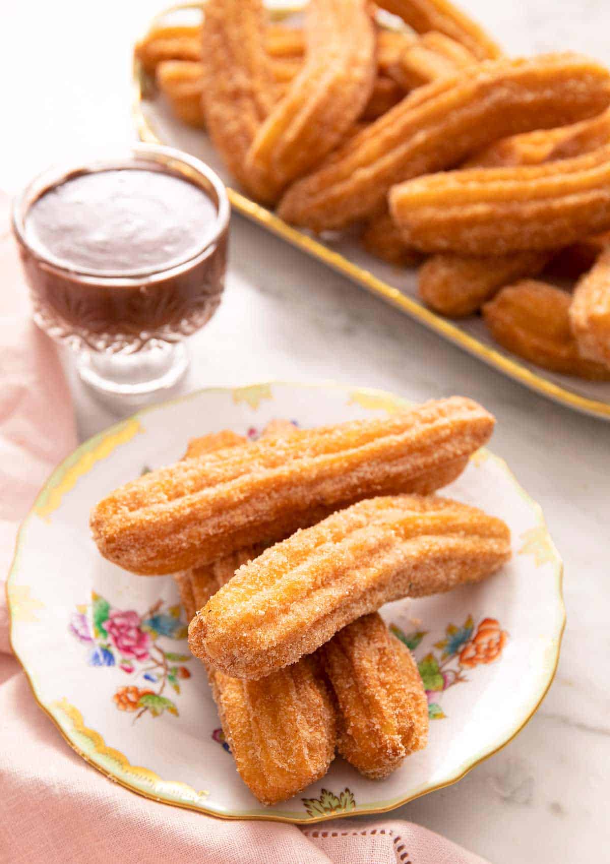 Churros on a plate with chocolate sauce in the background