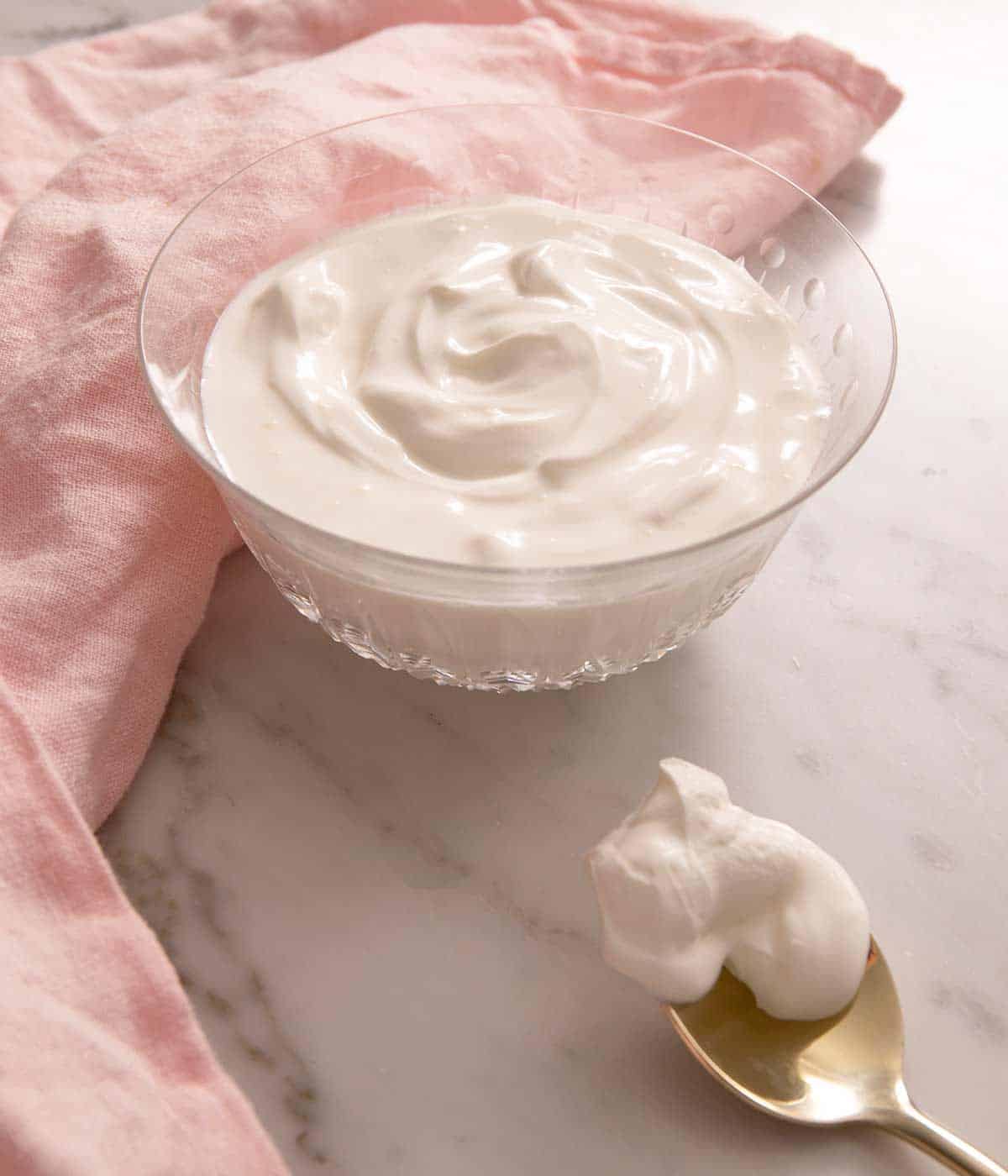 A bowl of homemade sour cream sitting on a marble work surface