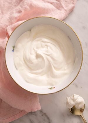 Sour cream in a bowl with a gold spoon beside it.