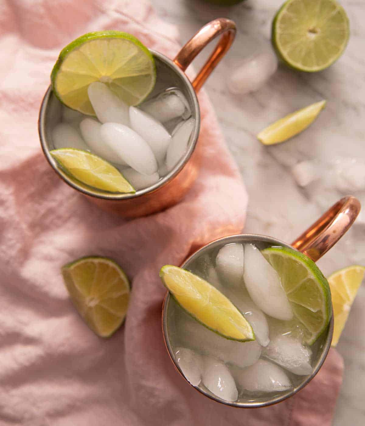 An overhead shot of two Moscow Mule cocktails filled with ice and lime wedges