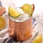a moscow mule in a copper mug with ice and limes