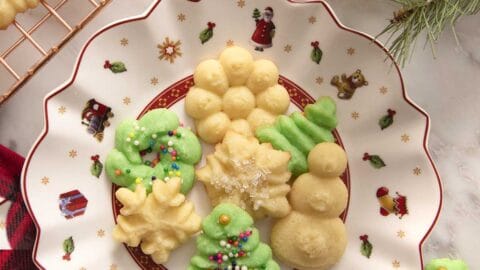 A white and red Christmas plate filled with green and white Christmas cookies.