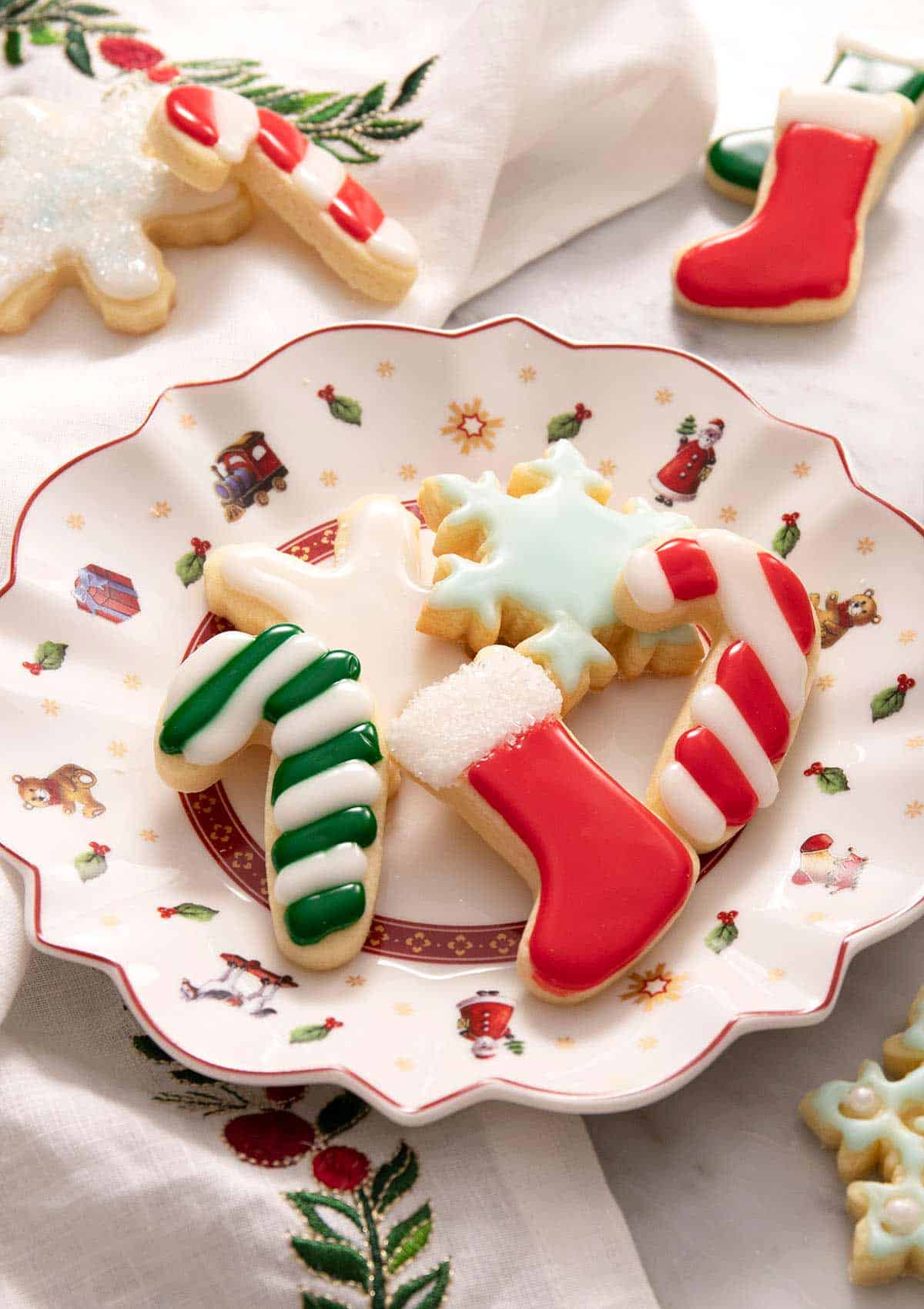 A side shot of Christmas sugar cookies with icing on a plate