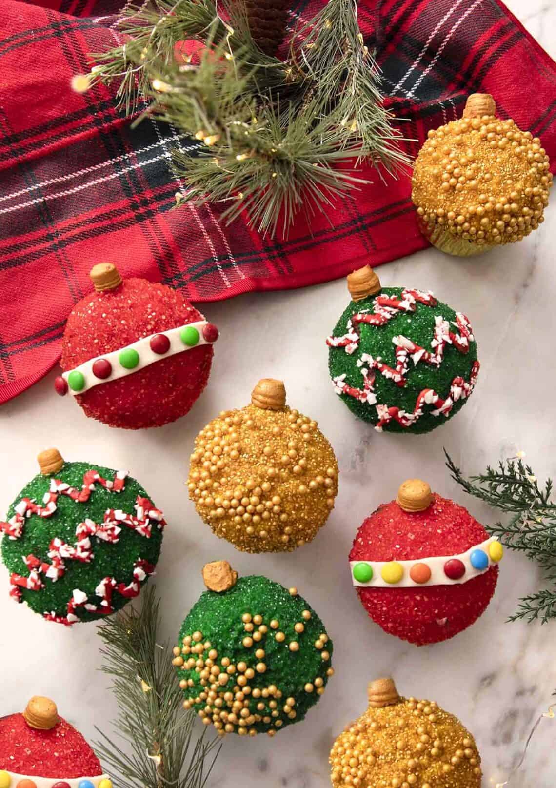A group of cupcakes decorated as colorful Christmas ornaments.