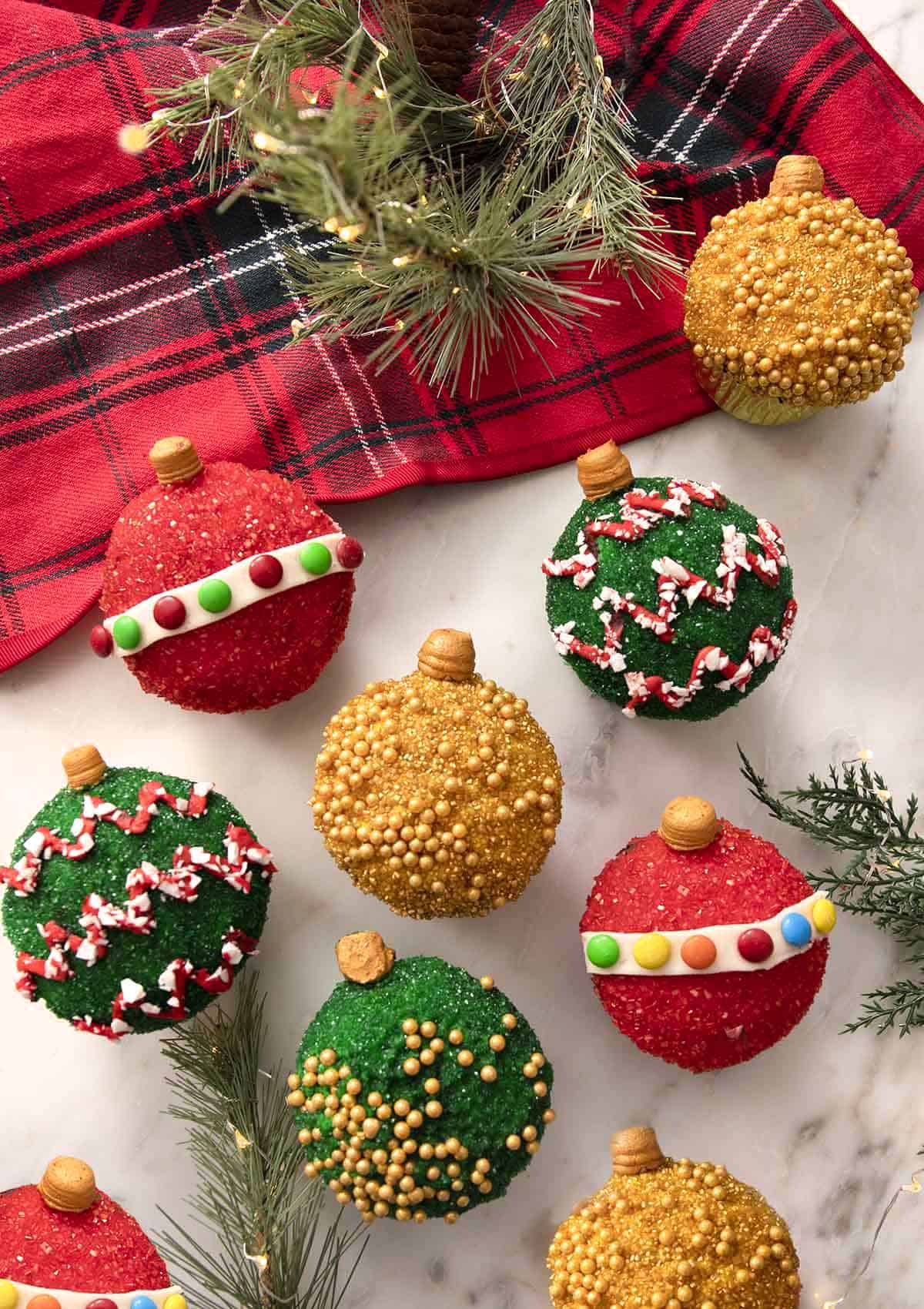 A group of cupcakes decorated as colorful Christmas ornaments.