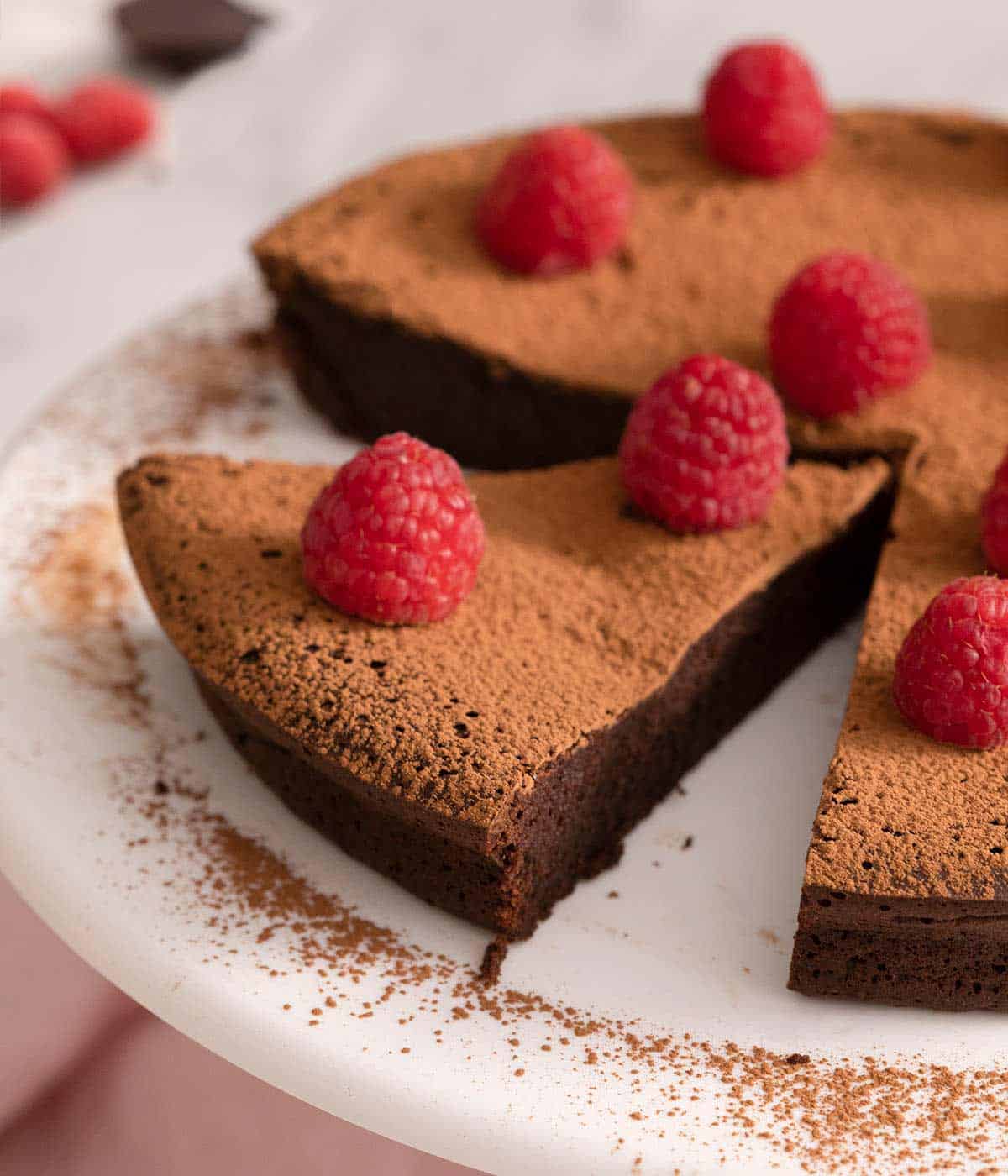 A close up of a slice of chocolate cake topped with raspberries