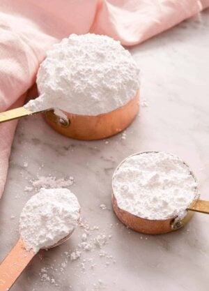 Powdered sugar in measuring cups and a measuring spoon