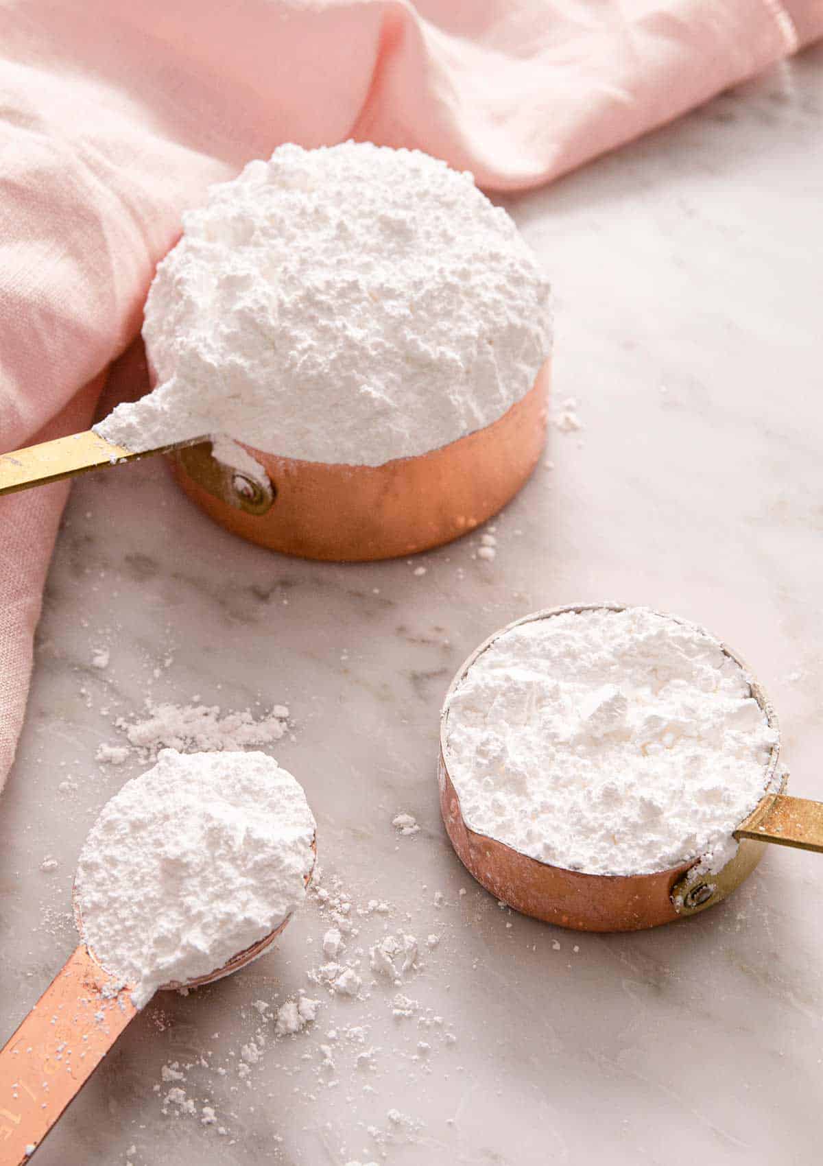 Powdered sugar in measuring cups and a measuring spoon
