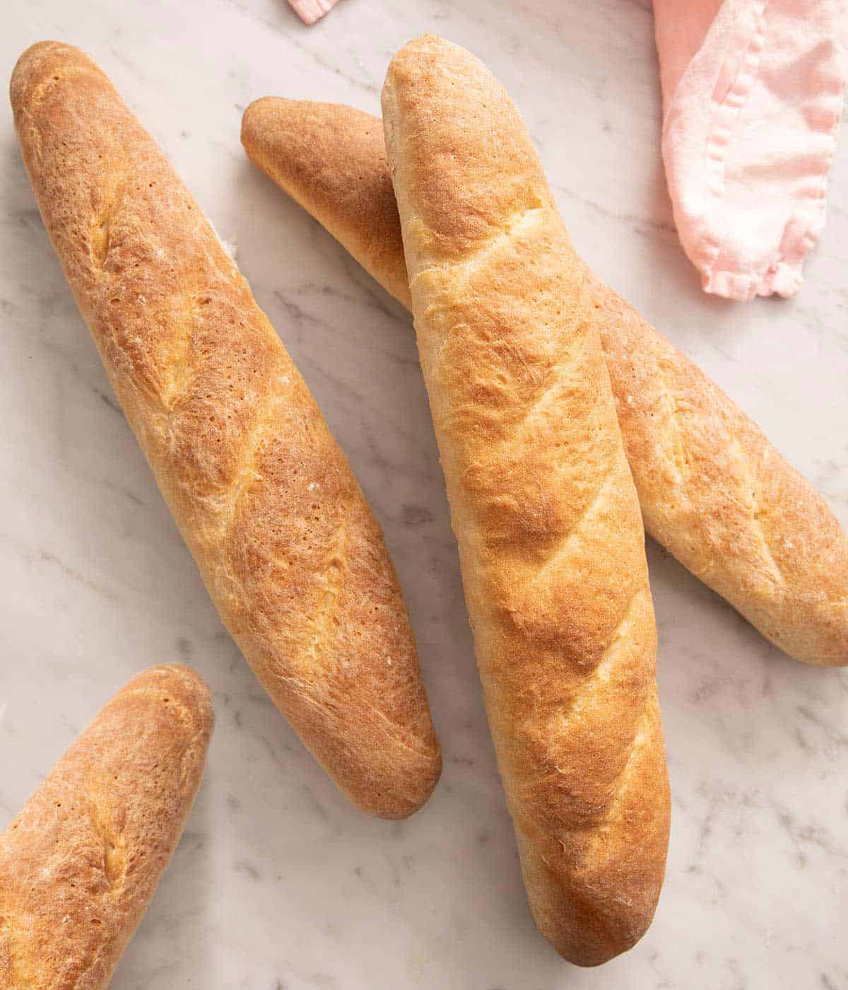 An overhead shot of French bread sticks on a marble surface