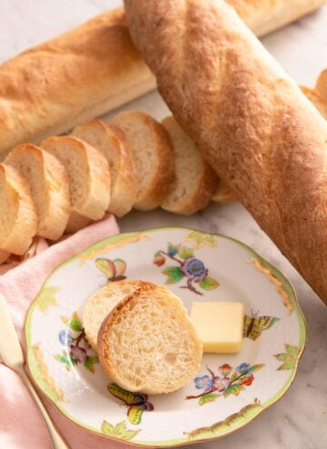A close up of French bread on a plate with slices of butter