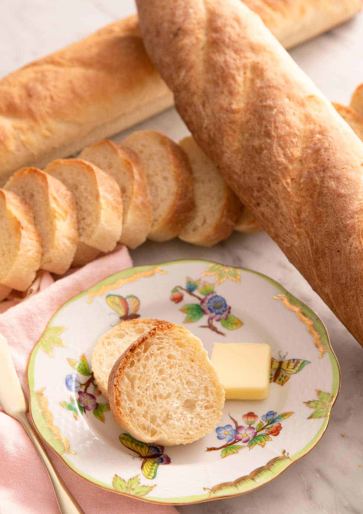 A close up of French bread on a plate with slices of butter