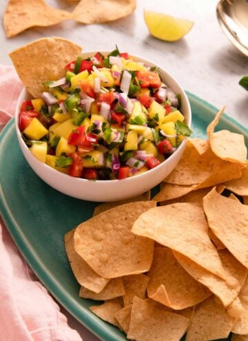 Mango salsa in a bowl with chips beside it