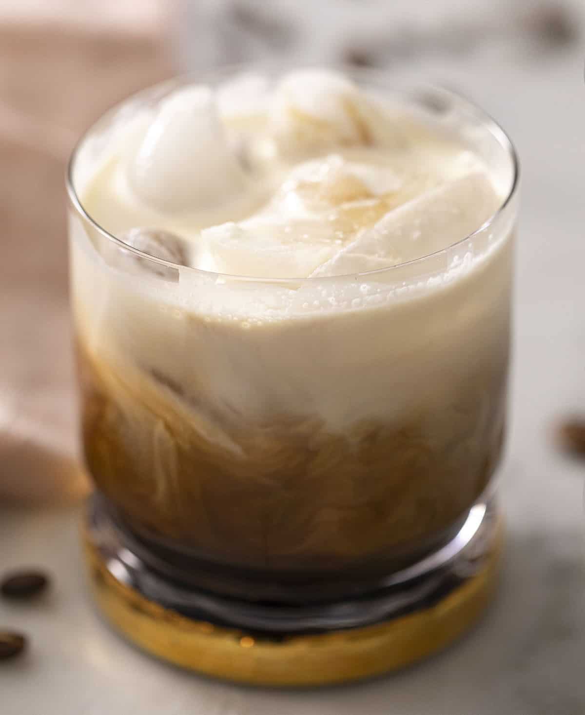 A close up of a coffee and vodka cocktail topped with whipped cream (White Russian)