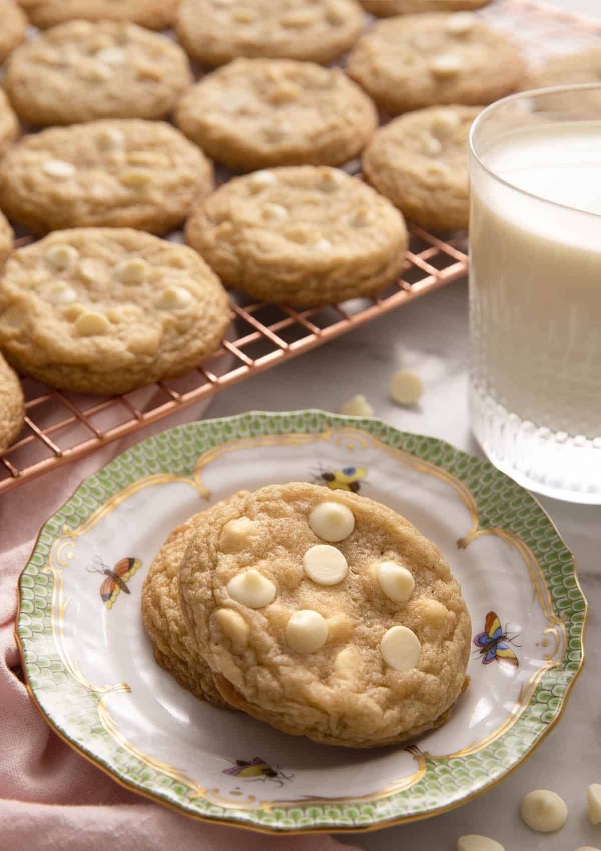 White chocolate chip cookies on a small plate and some on a cooling rack