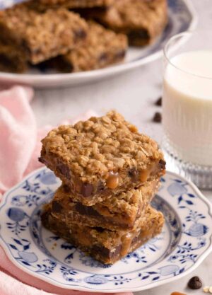 A stack of three carmelitas on a blue and white plate. A glass of milk on the side.