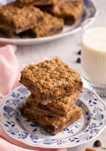 A stack of three carmelitas on a blue and white plate. A glass of milk on the side.