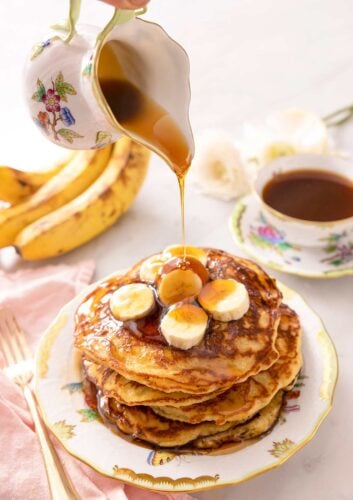 A jug powring syrup of banana pancakes