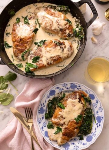 Overhead view of a braiser containing chicken florentine with a serving plated up beside it.