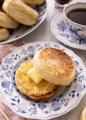 An English muffin cut in half and spread with butter on a plate.