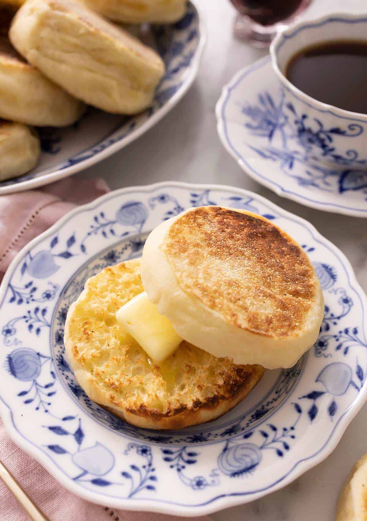 An English muffin cut in half and spread with butter on a plate