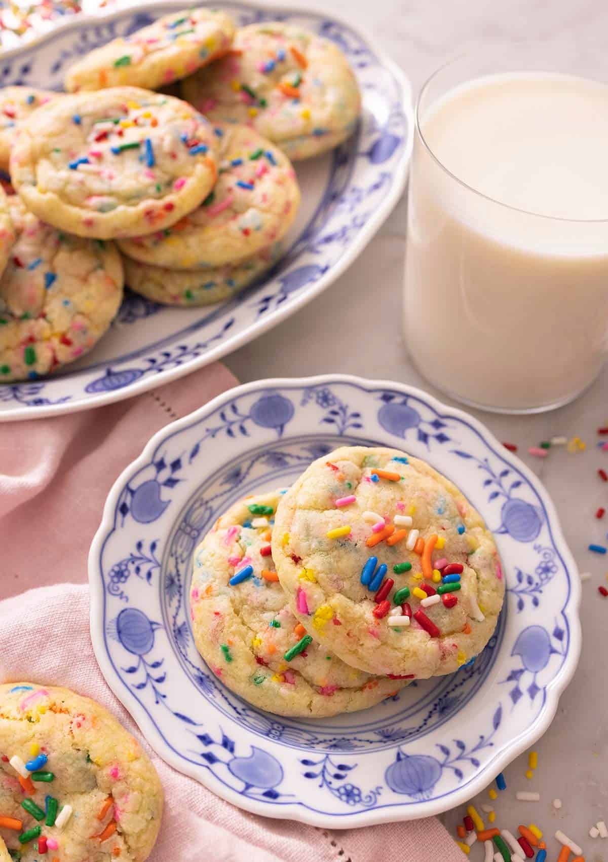 Funfetti cookies on a plate beside a glass of milk.