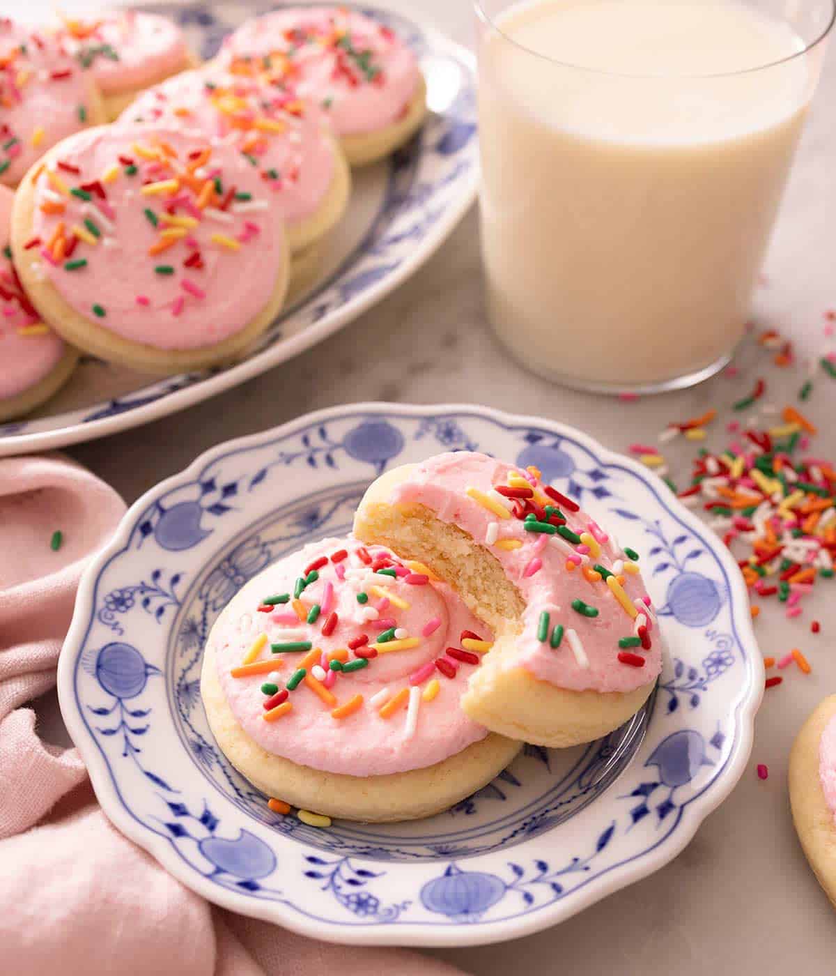 Two lofthouse cookies on a small blue plate one with a bite out