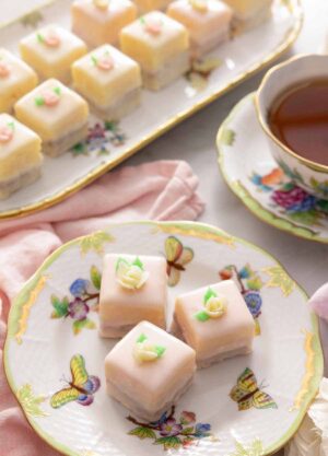 Overhead view of a serving platter of petit fours beside a plate with three.