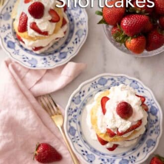 Pinterest graphic of the overhead view of two plates of strawberry shortcakes beside a bowl of strawberries.