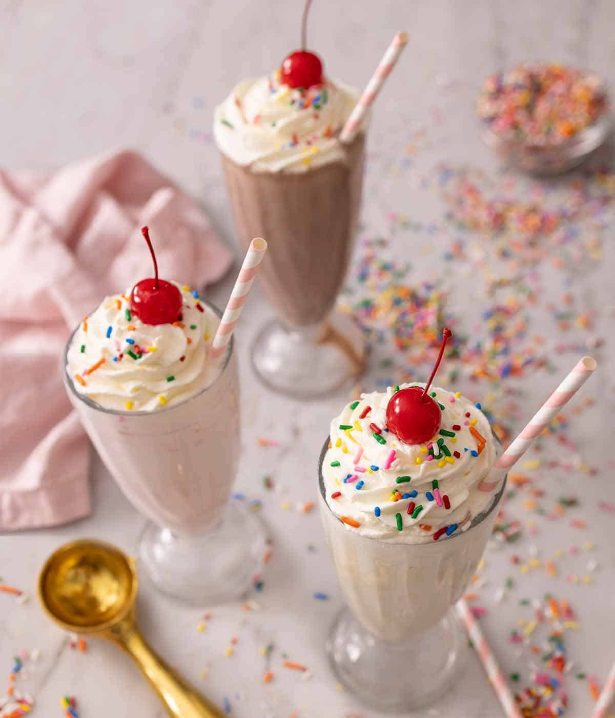 Angled view of the tops of three milkshakes, in chocolate, strawberry, and vanilla.