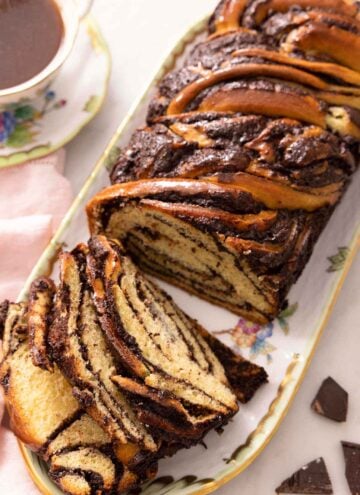 Overhead image of a babka on a long plate with three slices cut out and lying beside the loaf.