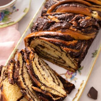 Pinterest graphic of a sliced babka in a long serving platter beside a cup of coffee.