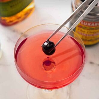 Pinterest graphic showing a tong placing a maraschino cherry into the middle of a glass of Manhattan.