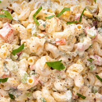 A Pinterest graphic of a close up view of macaroni salad with parsley on top.